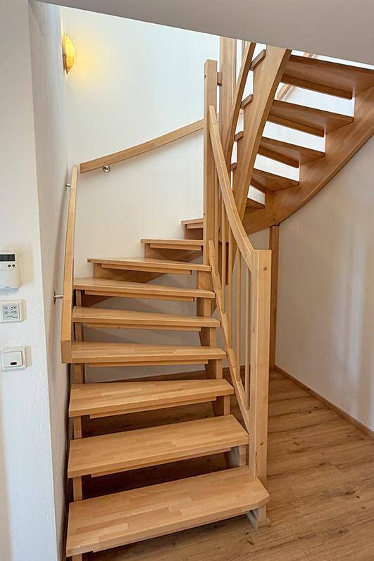 Helle Holztreppe mit Geländer, die die verschiedenen Ebenen des Hauses verbindet.