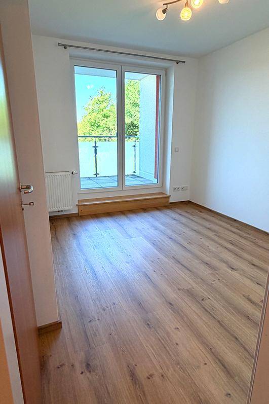 Helles Zimmer mit Laminatboden und Balkonzugang, ideal als Schlafzimmer.