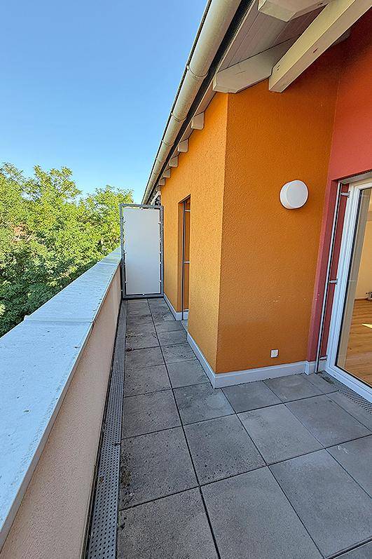 Geräumiger Balkon mit Fliesenboden und oranger Fassade, ideal für Entspannung im Freien.