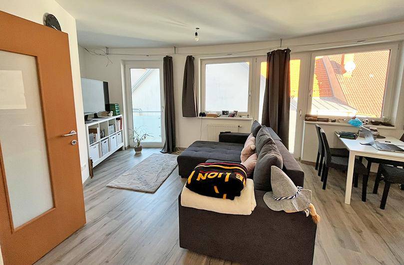Heller Wohn- und Essbereich mit Sofa, Esstisch und großen Fenstern für viel Tageslicht.