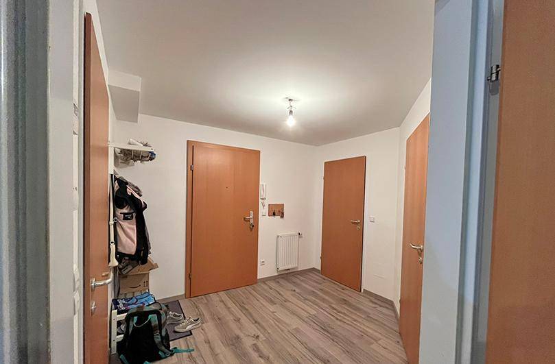 Heller Eingangsbereich mit Laminatboden und mehreren Holztüren, die zu den Zimmern führen.
