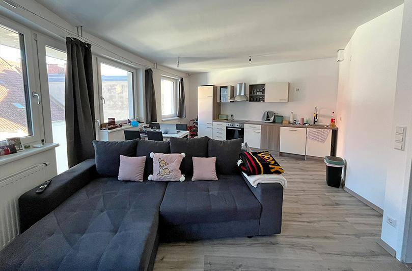 Offener Wohnbereich mit integrierter Küche, Sofa und Essbereich, ideal für geselliges Beisammensein.