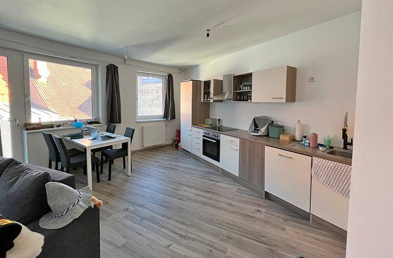 Moderne Einbauküche im offenen Wohnbereich mit hellen Schränken und integrierten Geräten.