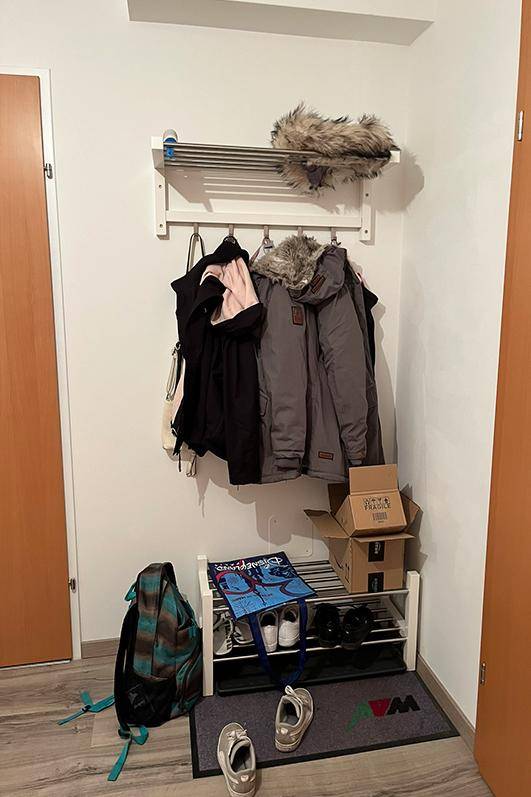 Praktischer Garderobenbereich im Flur mit Kleiderhaken und Schuhregal für den täglichen Gebrauch.