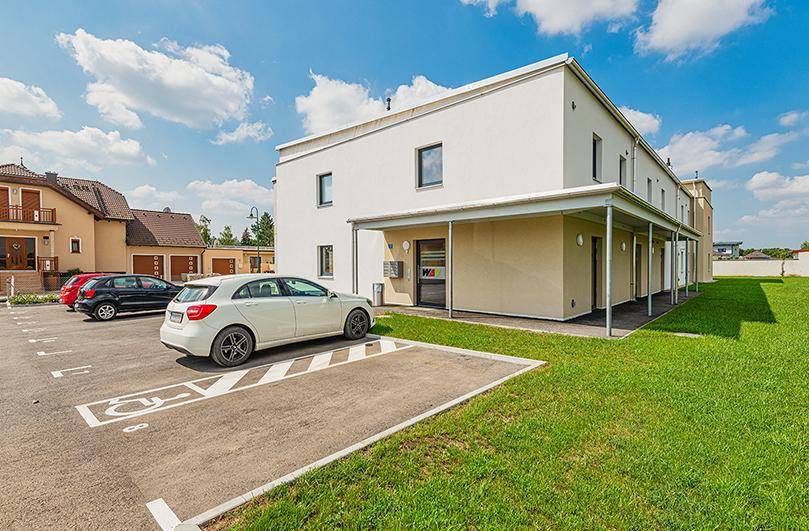 Außenansicht des Wohnhauses mit Parkplätzen, darunter ein barrierefreier Stellplatz.