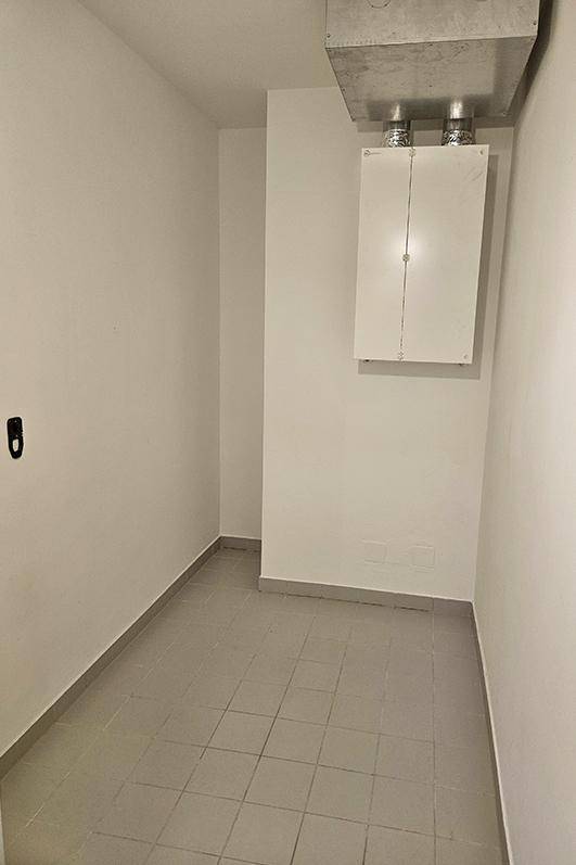 Praktischer Hauswirtschaftsraum mit Fliesenboden und sichtbarer Lüftungsanlage an der Decke.