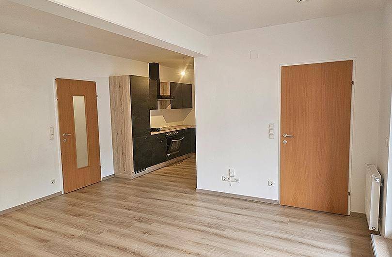 Offener Wohnbereich mit Laminatboden und Blick in die angrenzende moderne Küche.