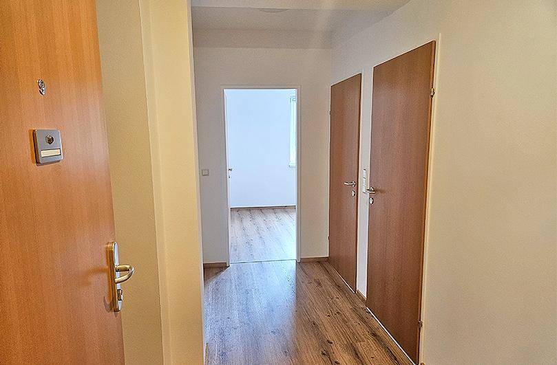 Heller Flur mit Laminatboden und mehreren Holztüren, der zu weiteren Räumen führt.