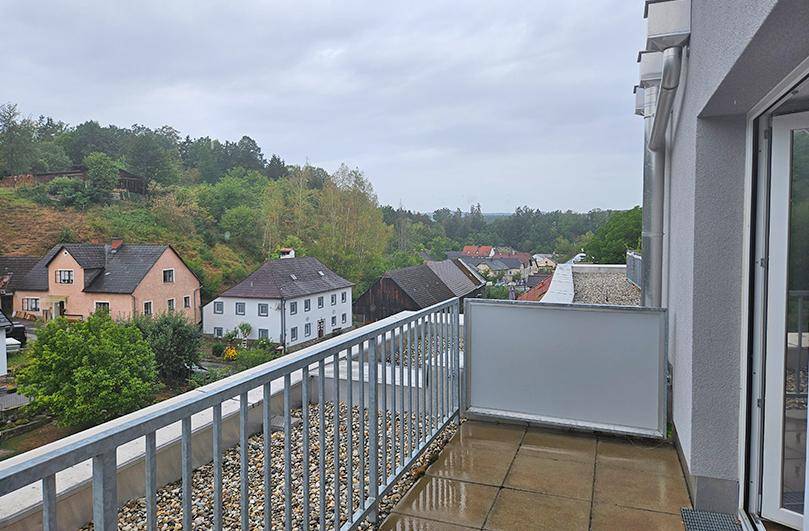 Balkon mit Fliesenboden und einem weiten Blick über die umliegende Landschaft und Häuser.