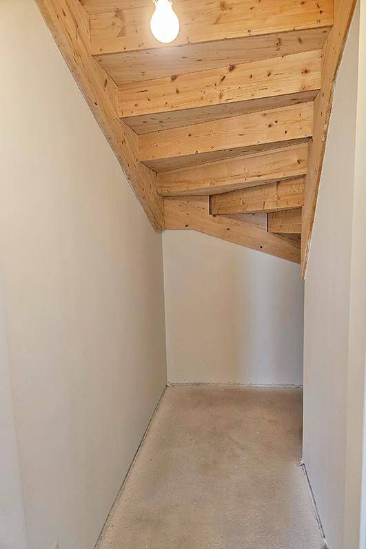 Abstellraum unter einer Holztreppe mit sichtbaren Holzbalken an der Decke.
