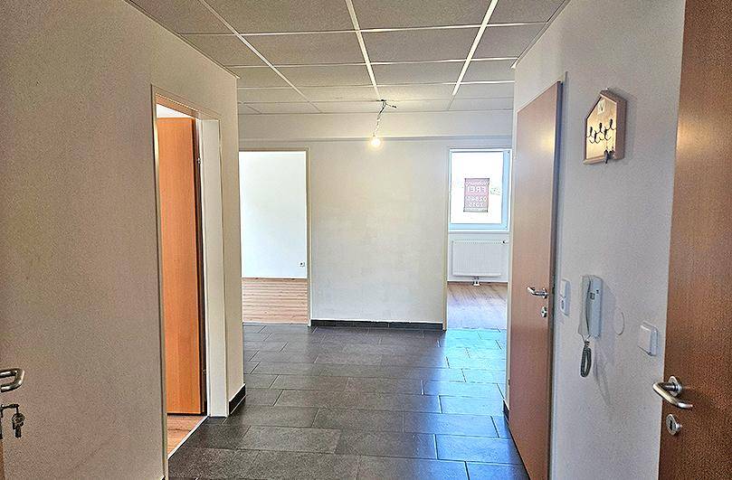 Heller Flur mit dunklen Fliesen und Zugang zu verschiedenen Räumen im Erdgeschoss.