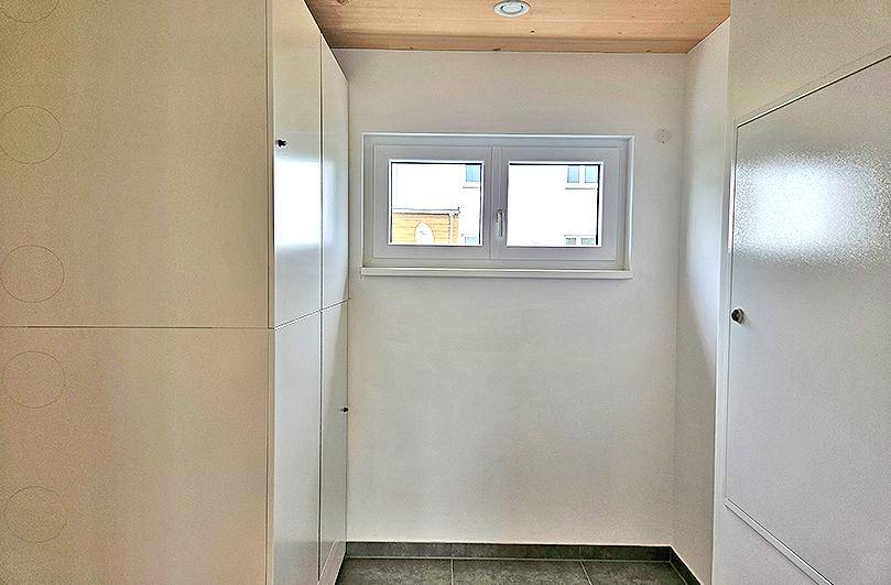 Praktischer Hauswirtschaftsraum mit Einbauschränken, kleinem Fenster und Fliesenboden.