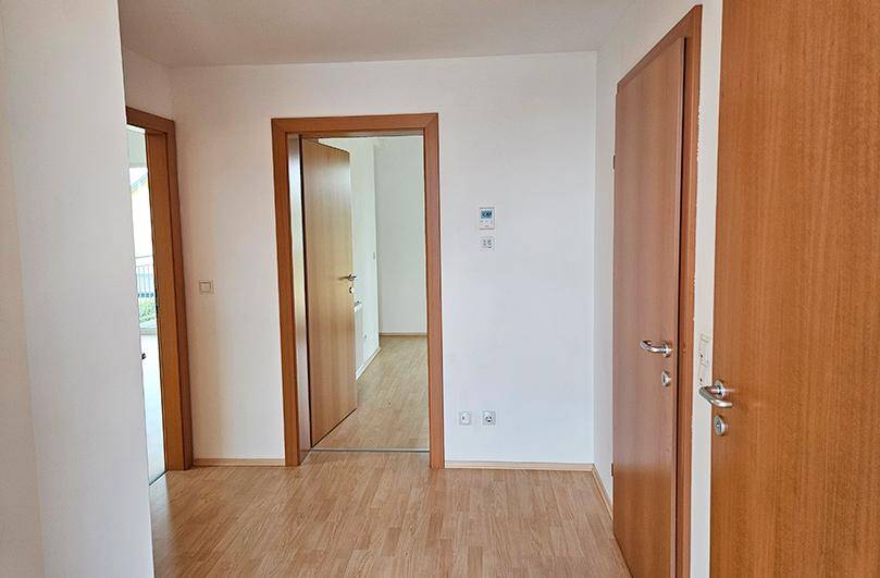 Heller Flur mit Holztüren und Laminatboden, der zu verschiedenen Räumen führt.