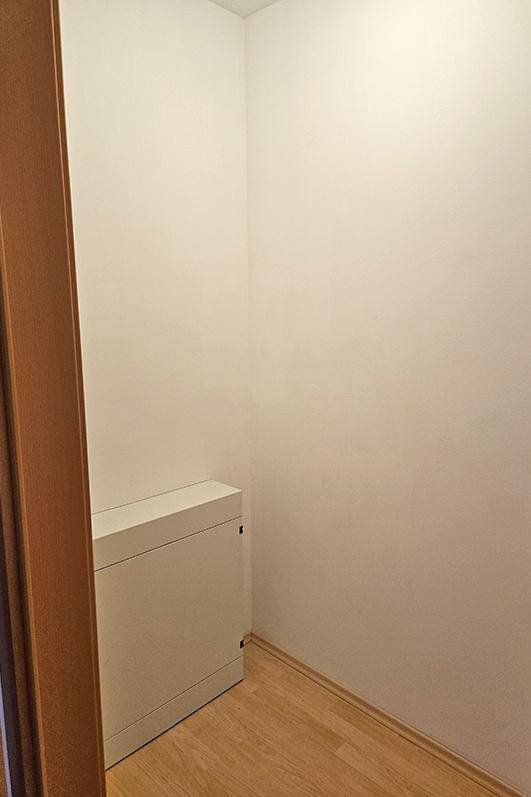 Kleiner Abstellraum mit Laminatboden und einer weißen Installationsbox an der Wand.
