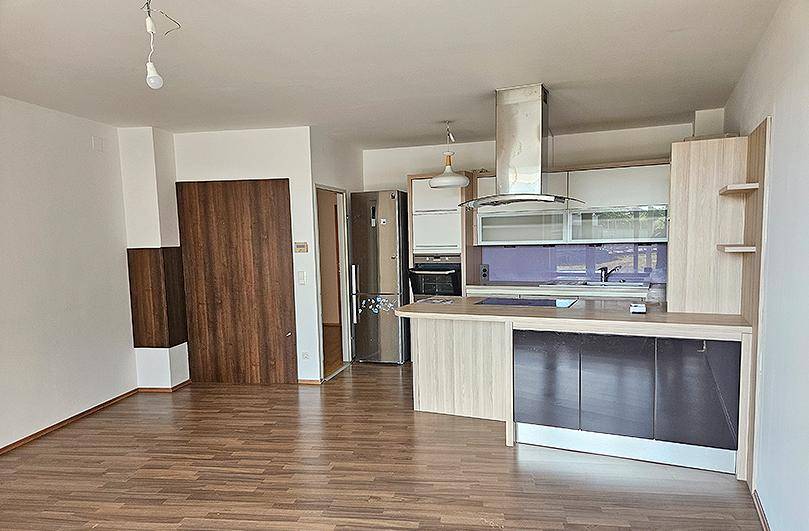 Offener Wohnbereich mit moderner Küche, integriertem Kühlschrank und durchgehendem Laminatboden.
