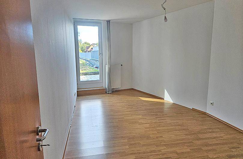 Helles Schlafzimmer mit Laminatboden und direktem Zugang zu einem Außenbereich.