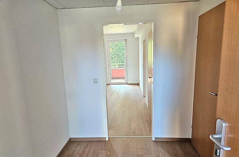 Heller Flur mit Holzboden und Blick durch eine Tür auf einen Balkon.