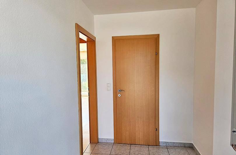 Helle Diele mit Fliesenboden und Holztüren, die zu weiteren Räumen führen.