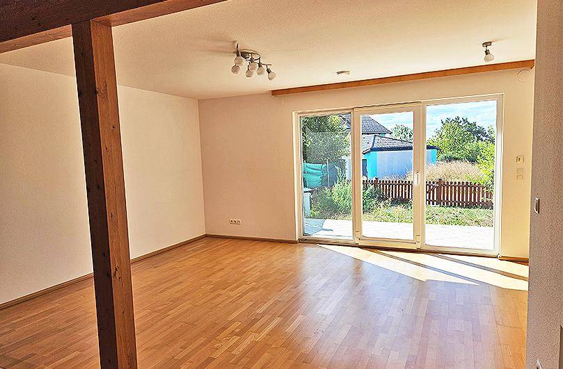 Heller Wohnraum mit Parkettboden und großen Schiebetüren zum Gartenbereich.