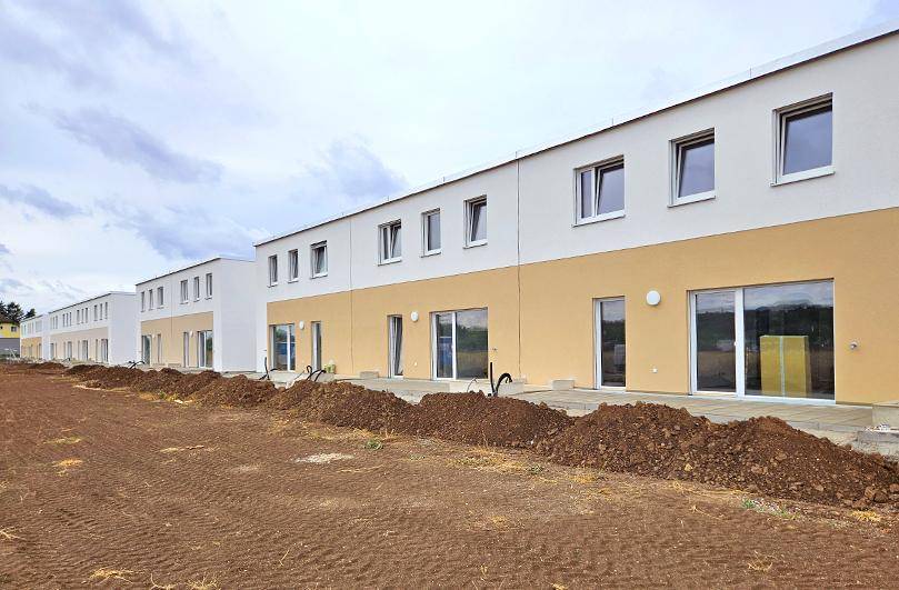 Reihenhäuser im Bau mit moderner Architektur und vorbereiteten Außenbereichen.