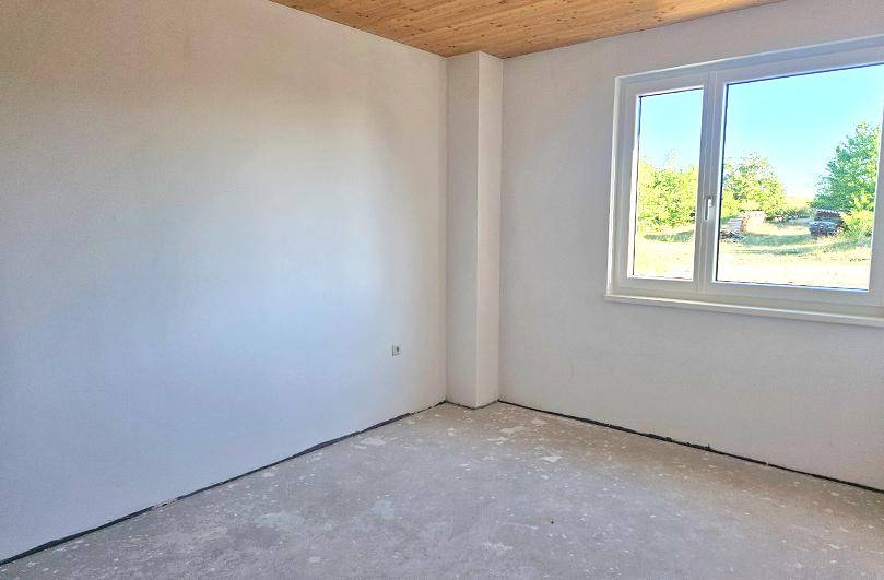 Helles, unfertiges Zimmer mit Fenster und Blick auf die umliegende Natur.