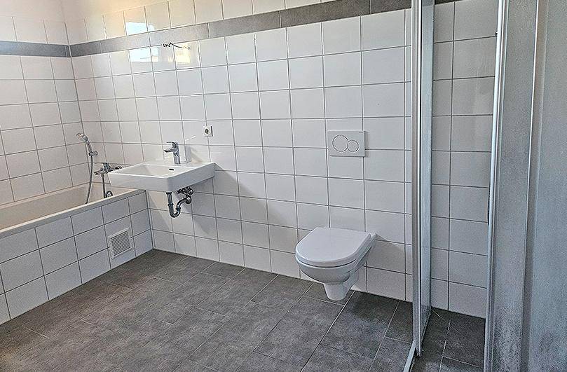 Modernes Badezimmer mit Badewanne, Toilette, Waschbecken und separater Duschkabine.