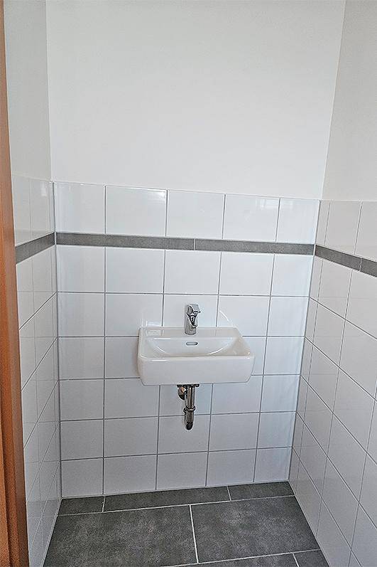 Kleines Badezimmer oder Gäste-WC mit weißen Wandfliesen und modernem Einzelwaschbecken.