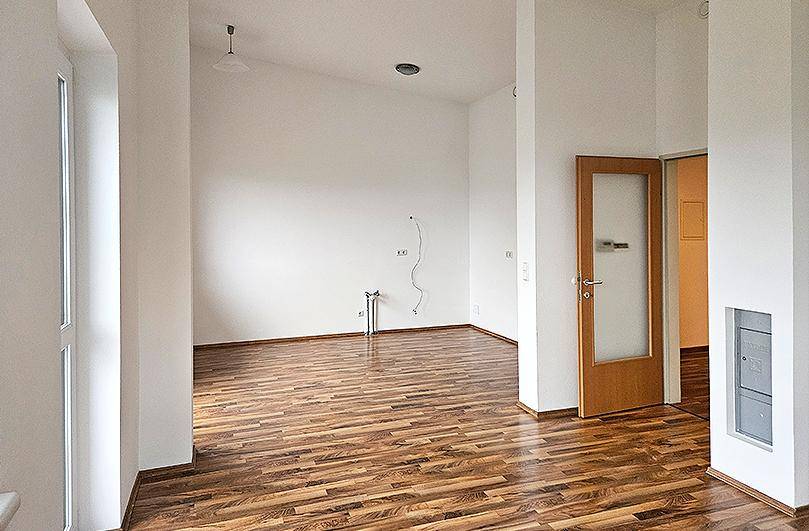 Geräumiger, leerer Raum mit Laminatboden und einer Tür mit Glaseinsatz, bereit zur Gestaltung.