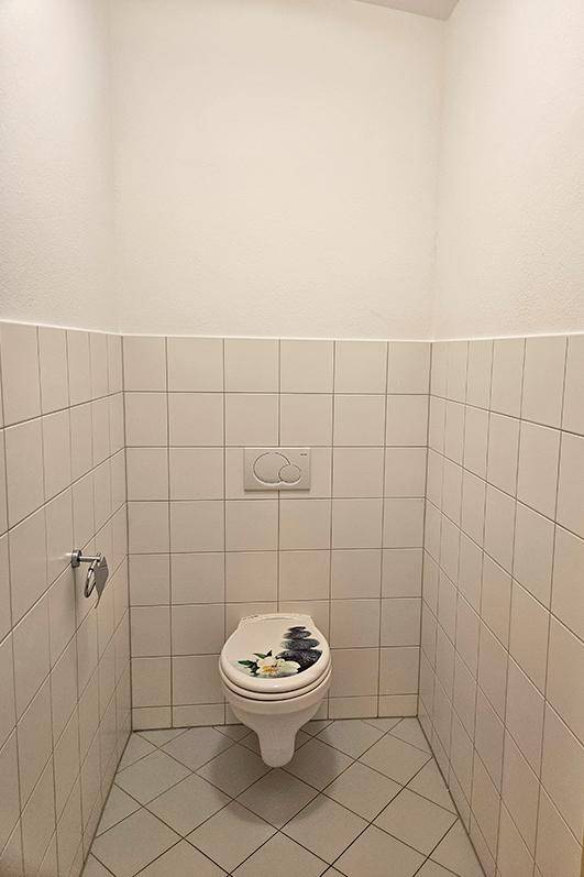 Kleines Gäste-WC mit gefliesten Wänden und einem wandmontierten WC mit floralem Dekor.