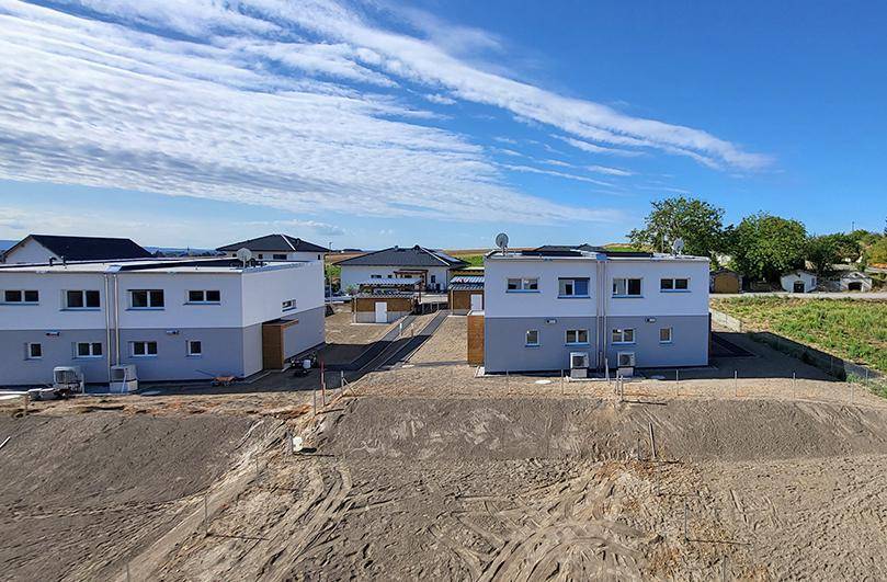 Überblick über eine Neubausiedlung mit mehreren modernen Reihenhäusern unter blauem Himmel.