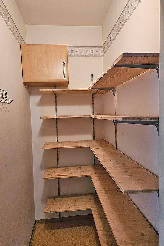 Praktischer Abstellraum mit maßgefertigten Holzregalen und einem kleinen Hängeschrank.