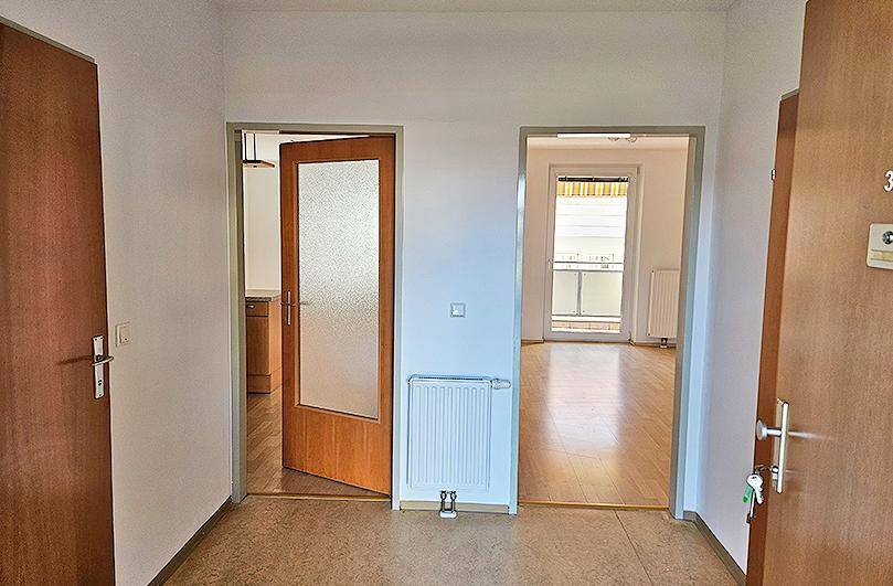 Eingangsbereich mit Laminatboden, der zu verschiedenen Zimmern der Wohnung führt.