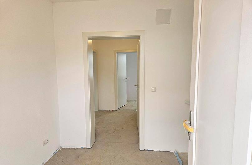 Unfertiger Flur in einem Neubau mit Blick in angrenzende, noch leere Räume.