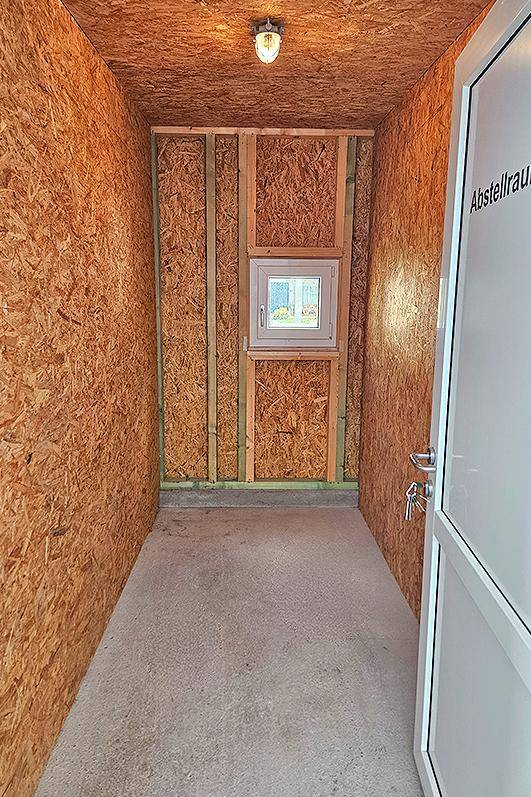 Praktischer Abstellraum mit OSB-Platten an Wänden und Decke, Betonboden und kleinem Fenster.