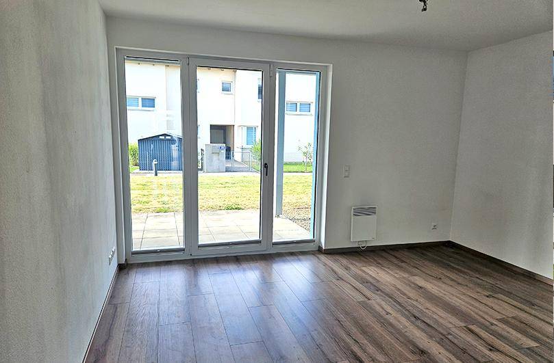 Lichtdurchfluteter Wohnbereich mit Laminatboden und Zugang zur Terrasse oder zum Garten.