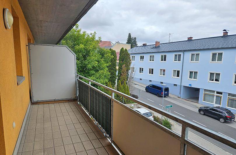 Balkon mit Fliesenboden und Blick auf die Straße sowie die gegenüberliegenden Gebäude der Stadt.