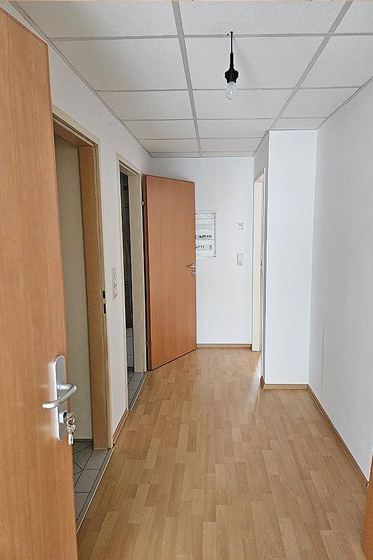 Heller Flur mit Laminatboden und mehreren Holztüren, der zu verschiedenen Räumen führt.