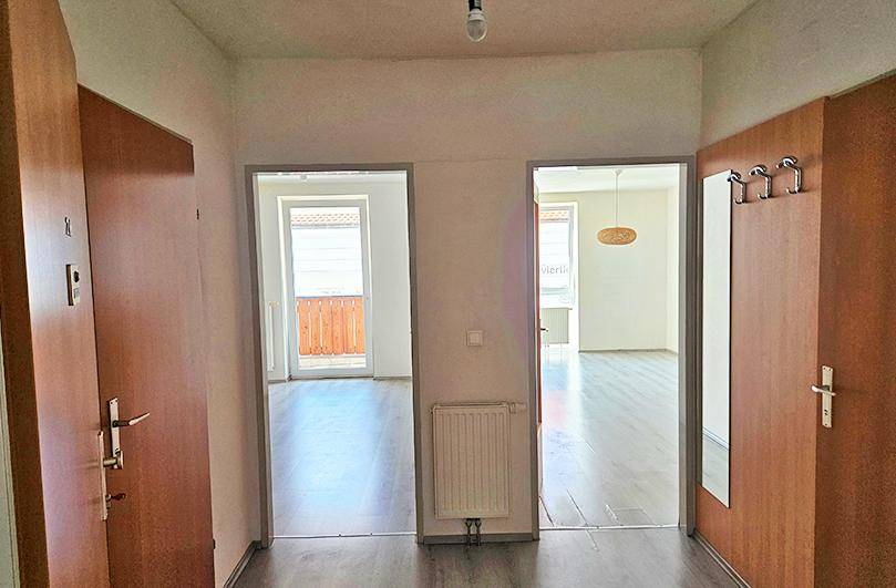 Heller Eingangsbereich mit Laminatboden und Zugang zu verschiedenen Zimmern, inklusive Heizkörper.