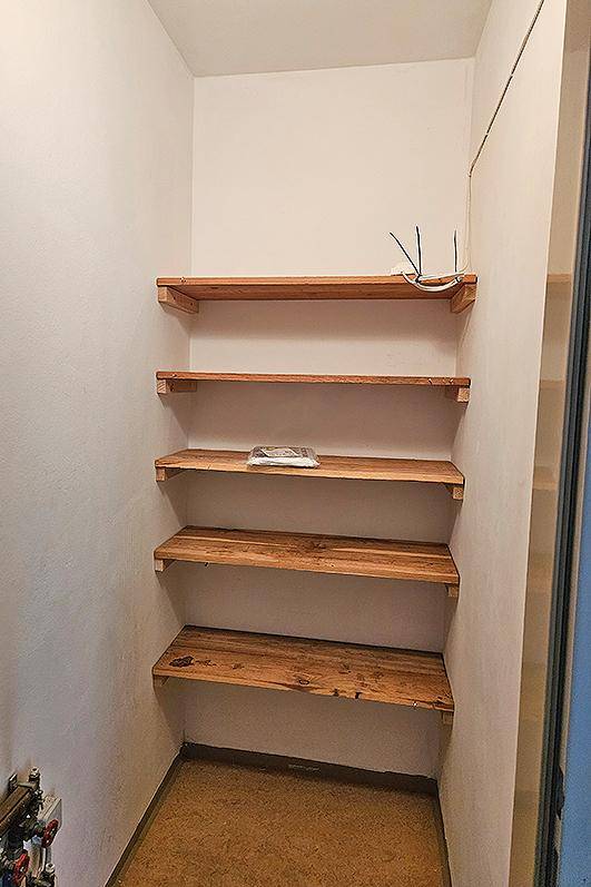 Praktischer Abstellraum mit mehreren Holzregalen für zusätzlichen Stauraum und Organisation.