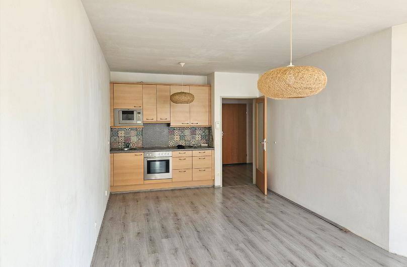 Funktionale Einbauküche mit Holzfronten, integrierten Geräten und farbigen Fliesen im Wohnbereich.