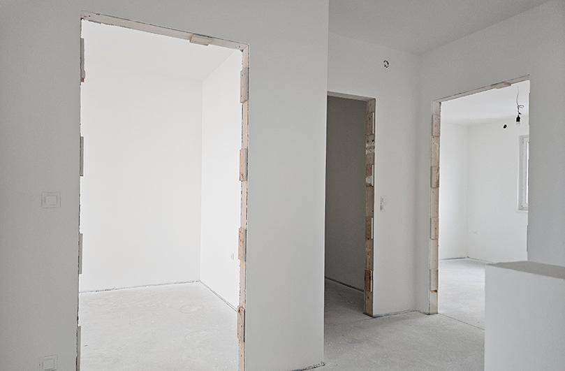 Zentraler Flurbereich im Rohbau mit mehreren Türöffnungen und unfertigem Betonboden.