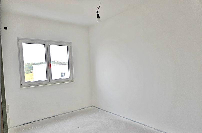 Unfertiges Zimmer mit weiß gestrichenen Wänden, Betonboden und einem Fenster mit weitem Ausblick.