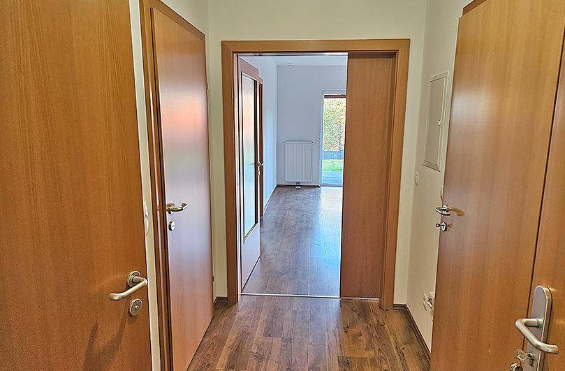 Heller Flur mit Laminatboden und Holztüren, der den Blick in einen weiteren Raum freigibt.