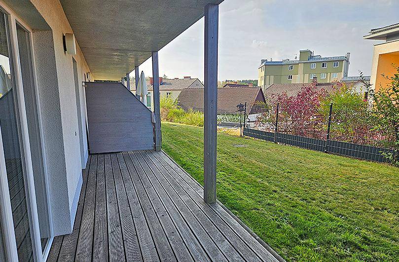 Lange Holzterrasse neben einem grünen Rasen mit Blick auf die umliegende Nachbarschaft.