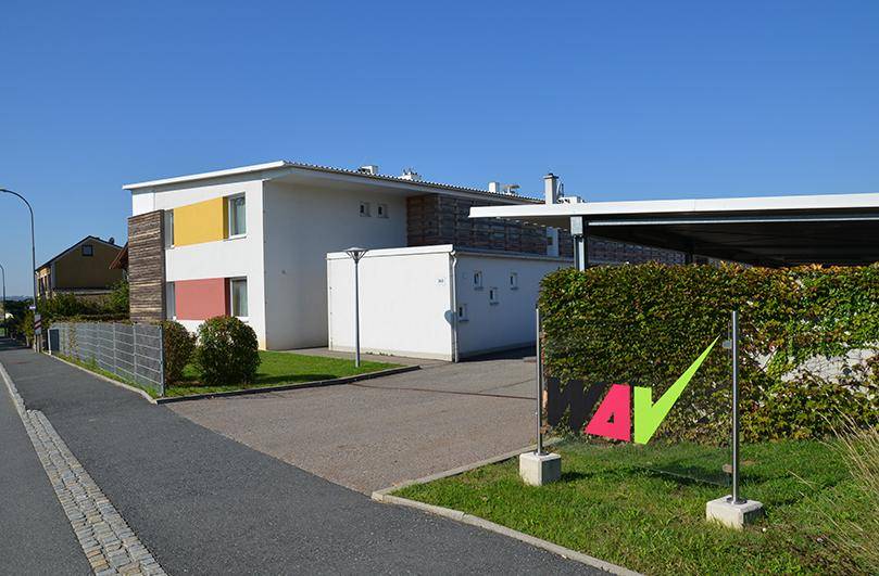 Modernes Wohnhaus mit farbigen Akzenten an der Fassade und einem Carport.