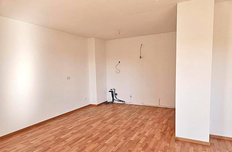 Leerer Raum mit Holzboden und vorbereiteten Anschlüssen, ideal für eine zukünftige Küche oder Wohnbereich.