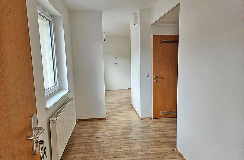 Heller Flur mit Laminatboden und Holztüren, der zu weiteren Räumen führt.