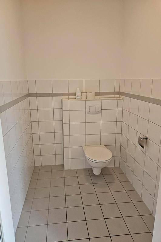 Kleines, gefliestes Gäste-WC mit wandhängender Toilette und Spülkasten.