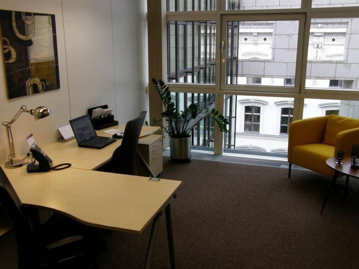 Helles Büro mit modernem Schreibtisch, bequemem gelben Sessel und großen Fenstern, die viel Tageslicht hereinlassen.