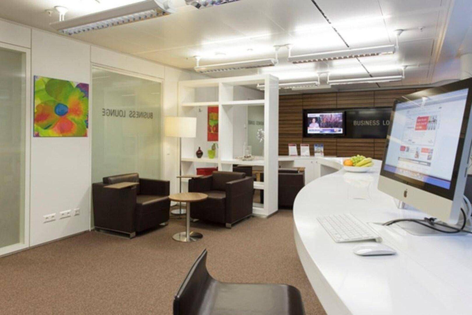 Moderne Business Lounge mit Empfangsbereich, bequemen Ledersesseln und einem Computerarbeitsplatz für Gäste.